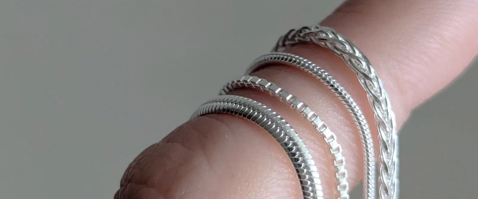 Las cuatro cadenas colgando de un dedo, para comparar qué tan delgadas son